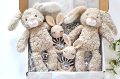 three stuffed animals in a box with flowers