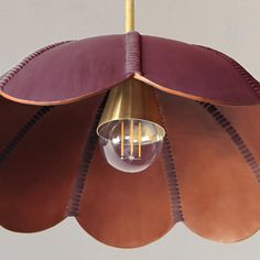 a light hanging from a ceiling fixture made out of brown leather and brass fittings