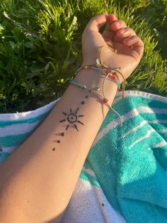 a woman's arm with a tattoo on it and the sun in the background