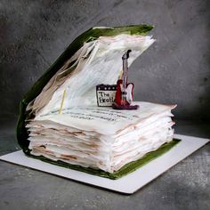 a stack of books that have been folded into the shape of a book with a guitar on top