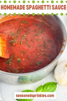 homemade spaghetti sauce in a pot with a wooden spoon and garlic on the side for garnish