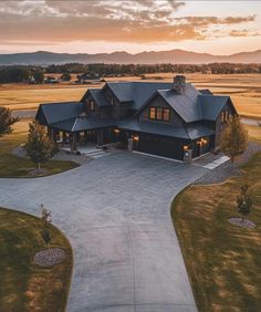 an aerial view of a large home in the middle of a field with mountains in the background