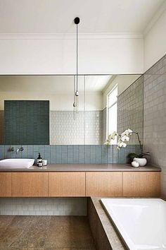 a bath room with two sinks and a bath tub under a large mirror on the wall