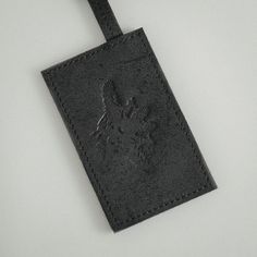 The charcoal black, raw matte calf leather is used inside out allowing the material to reveal factory marks and bruises, providing each piece with a unique character. Every piece is handcrafted in Budapest, Hungary. Wipe with a damp cloth, buff with a dry cloth, cleaning by a specialist.  SIZE AND FIT Width: 7 cm, Height: 11 cm, Strap Length: 50 cm FABRIC 100% Calf Leather  Shell, 100% Calf Leather Trim CARE Wipe with a damp cloth, buff with a dry cloth, cleaning by a specialist. Black Leather Card Holder With Engraved Logo, Black Rectangular Card Holder With Engraved Logo, Leather Card Holder With Engraved Logo, Rectangular Leather Card Holder With Leather Patch, Artisan Leather Rectangular Card Holder, Black Textured Leather Card Holder, Mens Luggage, Organza Top, A Perfect Circle