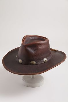 If ever there were a leather hat to handle the job, the strapless Raging Bull would be it. Made of rich, full-grain cowhide leather, this rugged hat is wonderfully durable, featuring a smooth hand, thick body, and superb protection from the elements. A tied hatband adorned with five conchos adds western appeal, while a cushioned sweatband keeps you cool and comfy in the heat of the moment. Rustic Leather Fedora For Rodeo, Brown Leather Fedora Hat, Leather Fedora Hats For Rodeo, Brown Leather Brimmed Fedora, Rugged Leather Wide Brim Fedora, Rugged Leather Wide-brim Fedora, Leather Brimmed Fedora For Rodeo, Western Leather Fedora With Flat Brim, Brown Leather Fedora For Rodeo