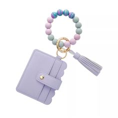 a pink wallet with a tasseled keychain and a beaded bracelet