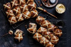 hot cross buns on a cooling rack next to butter and other dessert items with spoons