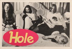 a group of women sitting on top of a bed in front of a red hole sign