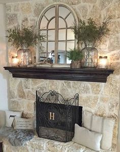 a stone fireplace with candles and plants on the mantel above it in a living room