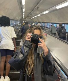 a woman taking a selfie while riding an escalator