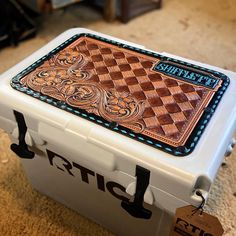 a white and brown checkerboard box sitting on top of a carpeted floor