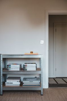 a metal shelf with books on top of it in front of a white wall and door