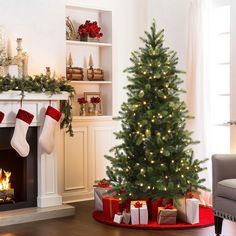 a christmas tree with stockings on it in front of a fireplace