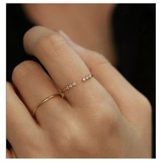 a woman's hand wearing a gold ring with three small diamonds on the band