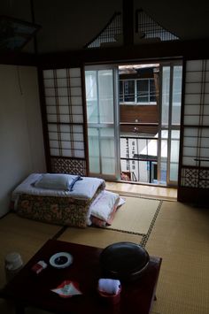 a room with two beds and a table in front of an open door that leads to another room