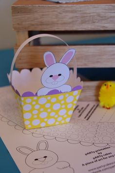 an easter basket sitting on top of a table next to a small yellow chickling