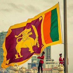 two men in red and yellow uniforms are holding a flag with the colors of sri