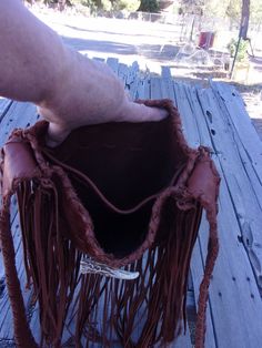 This boho fringed leather tote handbag is made is soft mahogany cowhide leather. It has fringe all around and measures 10 inches tall x 10 inches wide x 2.75 inches deep. There is an extra pocket inside. The beaded turtle totem is done mostly in shades of green glass seed beads and has a center focal of eagle feathers. There are also four directional colors inside the turtle totem. (Refer to the picture.) If you would like a different beaded rosette contact us. The beaded rosette is sewn on and Leather Fringe Hobo Bag For Festivals, Bohemian Bags With Beaded Fringe For Everyday Use, Bohemian Leather Shoulder Bag With Fringe, Brown Bohemian Satchel With Fringe, Brown Bohemian Fringe Satchel, Bohemian Brown Fringe Satchel, Handmade Leather Bohemian Bucket Bag, Festival Fringe Hobo Tote Bag, Bohemian Handmade Leather Bucket Bag