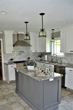 a large kitchen with an island in the middle and two pendant lights hanging from the ceiling