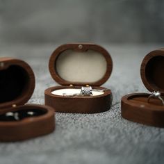 an open wooden ring box sitting on top of a table next to two wedding rings