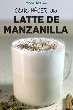 there is a cup of latte de manzanilla next to some cinnamons