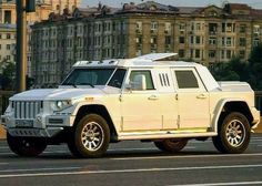 a white hummer is parked on the side of the road in front of some buildings