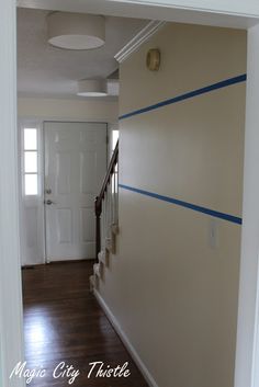 an empty hallway with blue tape on the wall and white door in the background,