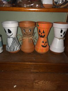 several pots with faces painted on them sitting on a shelf