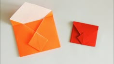 an origami envelope next to a folded piece of paper on a white surface