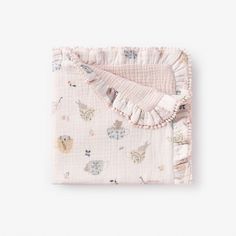 a blanket with animals on it and ruffles around the edges is laying on a white surface