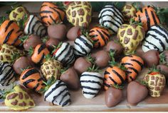 chocolate covered strawberries are arranged on a cutting board with zebra print designs and oranges