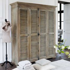 a dress form and some white pillows in a room with wooden doors on the wall