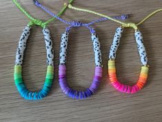 three different colored bracelets are hanging on a wooden table with some string attached to them