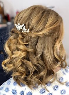 the back of a woman's head with wavy hair and flowers in her hair