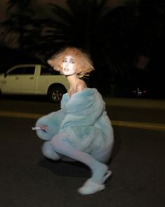 a woman dressed in blue poses on the street