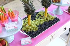 fruit and veggies are displayed in trays on a table at a party