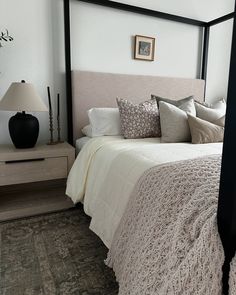 a bedroom with a four poster bed and white walls