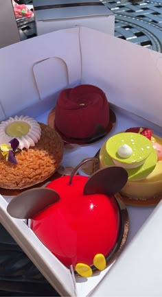 three desserts in a white box on a table