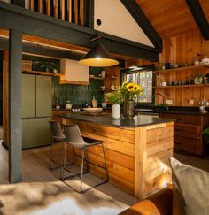 a kitchen with wooden walls and flooring next to an open living room, dining area