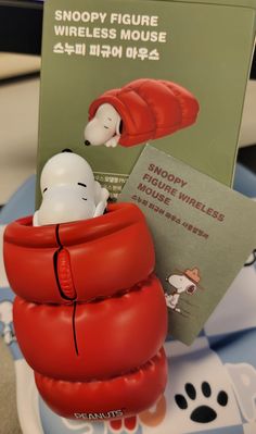 a snoopy figurine in a red life jacket with a book on it