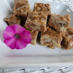 a white plate topped with pieces of food next to a pink flower