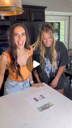 two women are standing in the kitchen and smiling