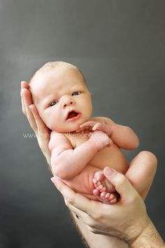 a man holding a baby in his hands while he holds it up to the camera