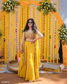 a woman standing in front of a decorated stage with flowers and garlands on it