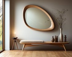 a wooden table with a mirror and vase on it in front of a large window