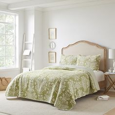 a bedroom with white walls and green bedding on the floor, along with a large window