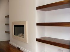 a room with some shelves and a fire place in the corner on one side, an open shelf to the other