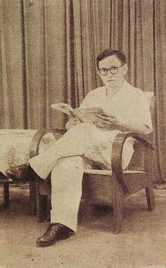 an old photo of a man sitting in a chair with a book on his lap