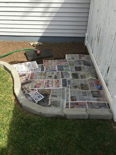 a pile of newspapers sitting on top of a grass covered ground next to a building