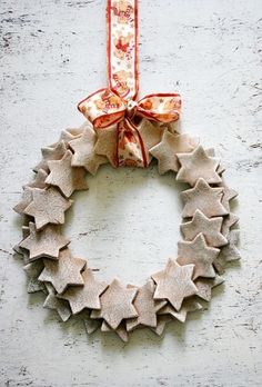 a christmas wreath hanging on the side of a white wall with red ribbon and bows